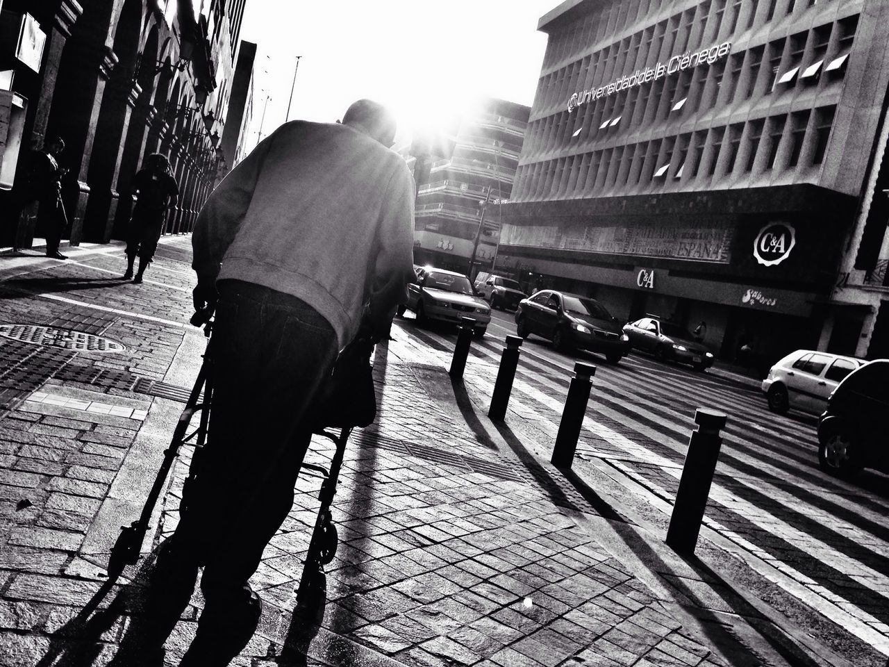 building exterior, architecture, built structure, city, lifestyles, sunlight, city life, street, walking, leisure activity, person, rear view, men, shadow, sidewalk, full length, sunny, sunbeam