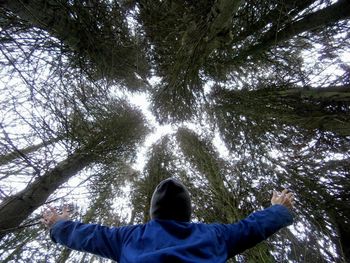 Man with arms outstretched against tall trees