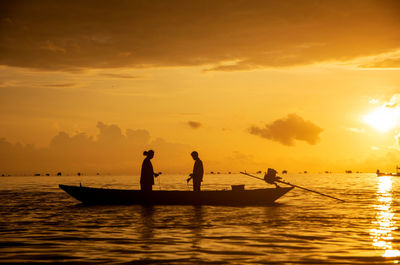 Silhouette fishermen on wooden boat preparing casting a net catching fish in the early morning