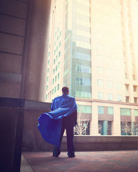 Rear view of man standing against wall in city