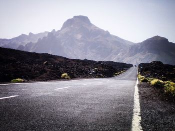 Road leading towards mountains against sky