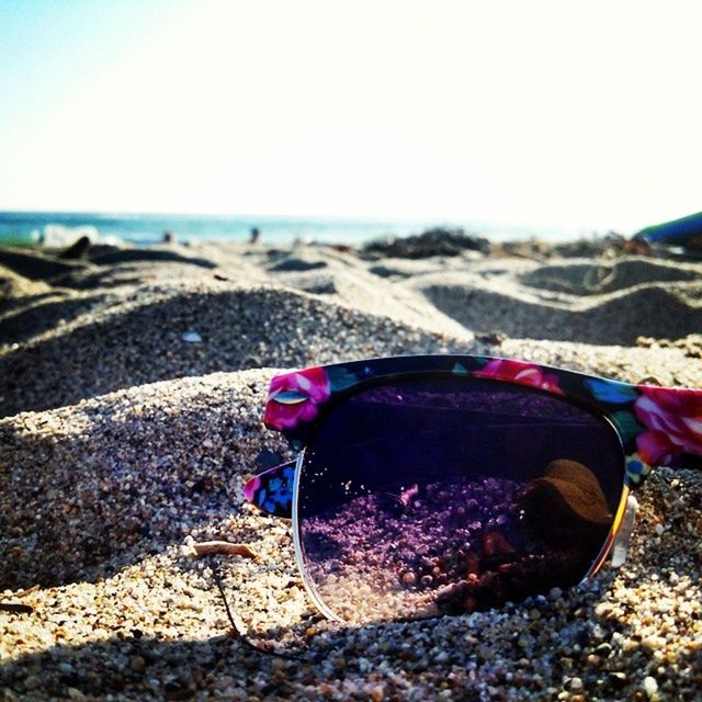 beach, sand, shore, sea, clear sky, sunlight, nature, outdoors, water, day, sky, stone - object, one person, pink color, one animal, tranquility, pebble, beauty in nature, horizon over water, close-up