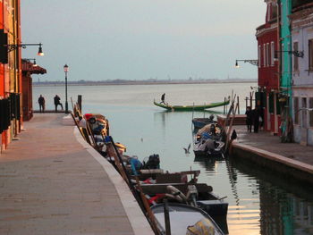 People on boats moored in sea against clear sky