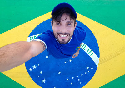 Directly above portrait of man smiling while standing on brazilian flag