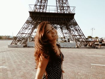 Side view of happy young woman standing against eiffel tower