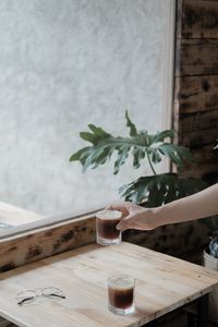 Cropped image of person holding drink on table