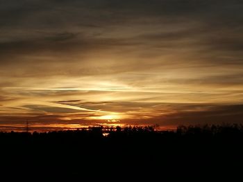 Silhouette landscape against dramatic sky during sunset