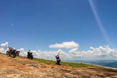 People riding bicycle by sea against sky