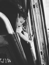 Side view of young woman looking through window