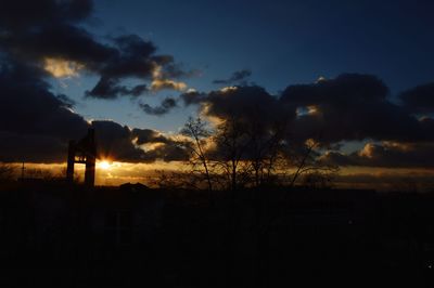 Silhouette trees on field against sky during sunset