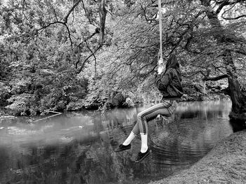 Woman in lake by trees in forest