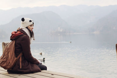 Side view of woman sitting on pier over sea