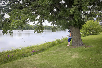 Woman standing by lake against trees