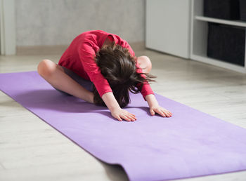 Side view of woman sitting on floor at home