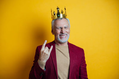 Portrait of smiling man gesturing against yellow background