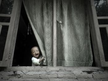 Low angle view of cute kid looking through window