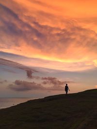 Silhouette people standing on shore by sea against sky during sunset