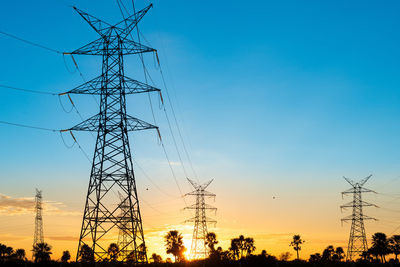 Low angle view of electricity pylon against sky during sunset