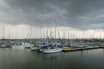 Sailboats moored in harbor against sky