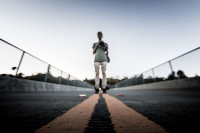 Rear view of woman on footbridge against clear sky