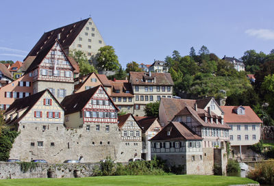 Houses on field by buildings in town against sky