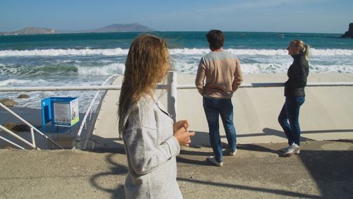 Rear view of women standing at beach