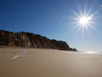 Scenic view of beach against sky on sunny day