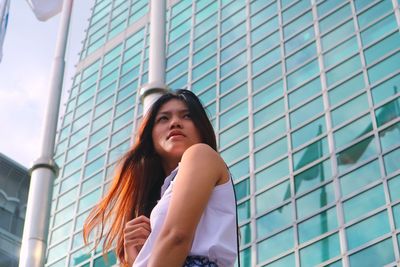 Low angle view of young woman standing in front of building