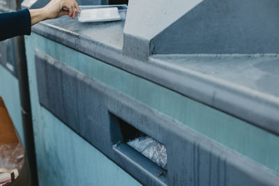 Woman's hand putting rubbish into recycling bin