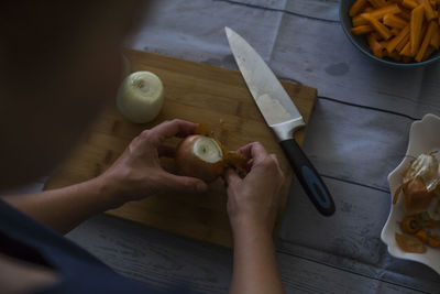 Midsection of woman peeling onion in kitchen