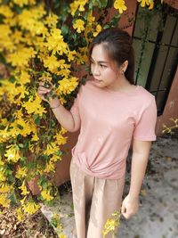 Low angle view of girl standing on yellow flowering plants