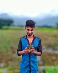 Young man using mobile phone on field