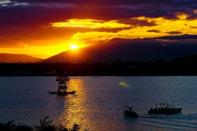 Silhouette boats in sea against sky during sunset