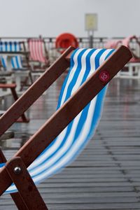 Close-up of deck chair on pier 