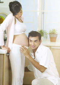 Man listening to belly of pregnant woman at home