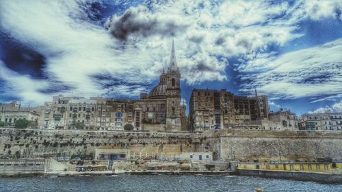 Buildings in city against cloudy sky