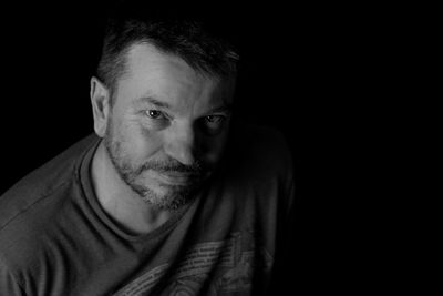 Close-up portrait of man wearing black background