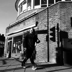 Full length of man on footpath against building in city