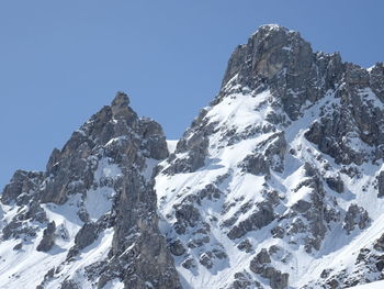 Low angle view of snowcapped mountains against clear sky