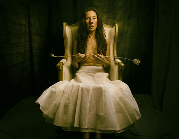 Woman in white skirt sitting in an antique armchair