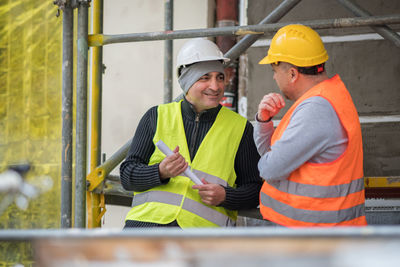 Engineers discussing while standing at construction site