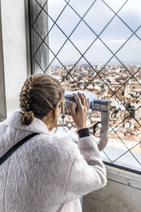 Woman looking city through binoculars