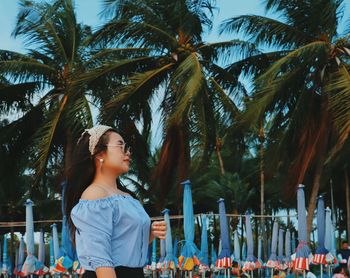 Woman standing by palm trees