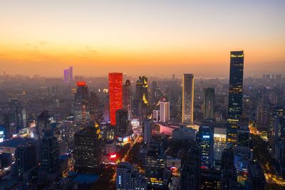 Aerial view of illuminated buildings in city against sky during sunset