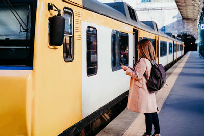 Woman standing by train at railroad station