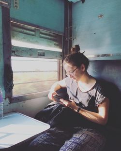 Young woman using digital tablet while traveling in train