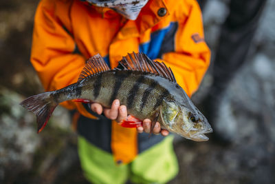 Midsection of man holding fish