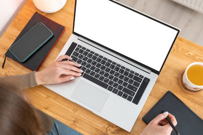 Unrecognizable brunette girl drawing picture or retouching on graphic tablet.