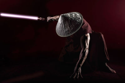 Muscular man holding laser sword against red background