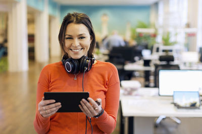 Portrait of happy businesswoman holding digital tablet in creative office